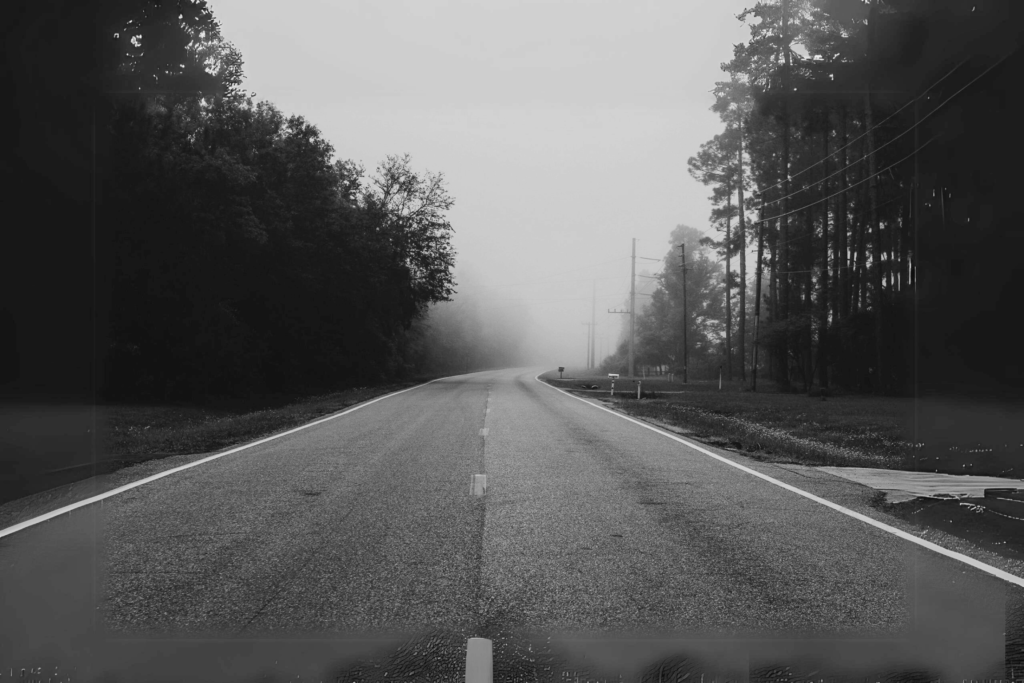 Understanding Reiki and Its Connection to Depression A deserted, straight road surrounded by whispering trees disappears into the misty fog under an overcast sky, much like the soothing journey of a reiki session.