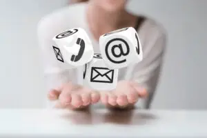 A person holds three floating cubes adorned with email, phone, and at symbols, radiating energy that bridges modern communication methods with the healing power of connection.