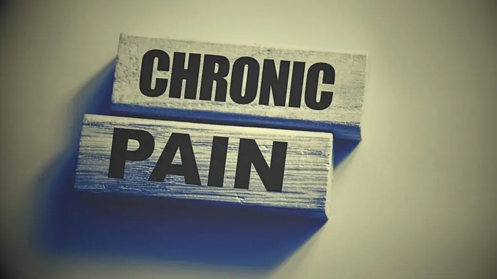 Two wooden blocks display the words "CHRONIC PAIN" in bold black letters against a plain background, symbolizing the importance of Chronic Pain Management for improved well-being.