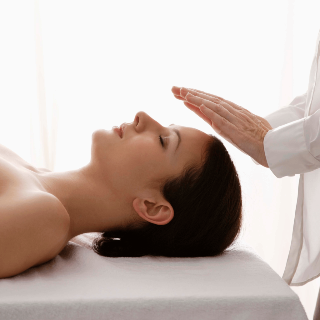 A person lies down with eyes closed, possibly seeking relief from acute pain, while another's hands hover over their head in an energy healing session.